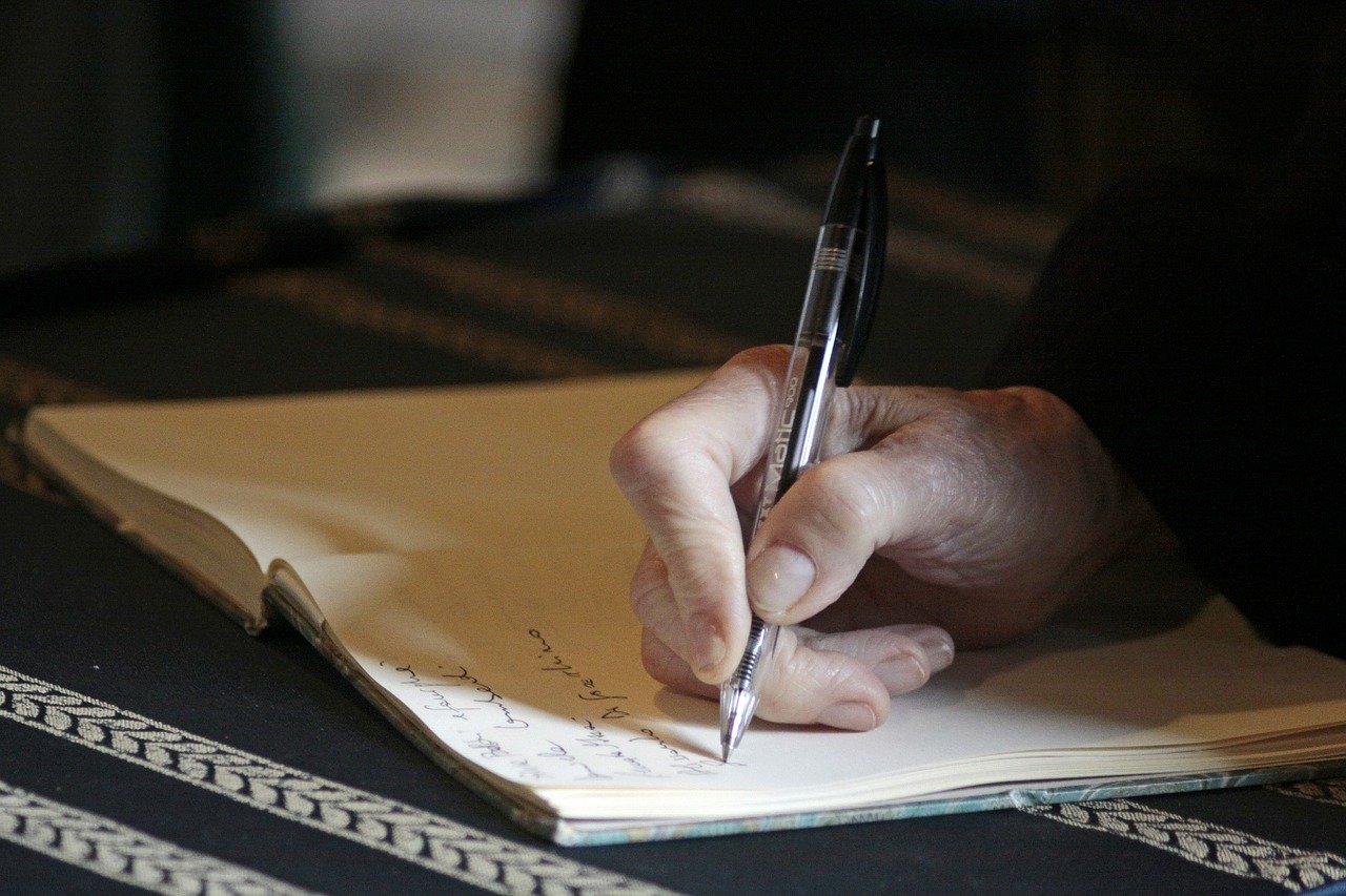 ペンでノートに文字を書く人
