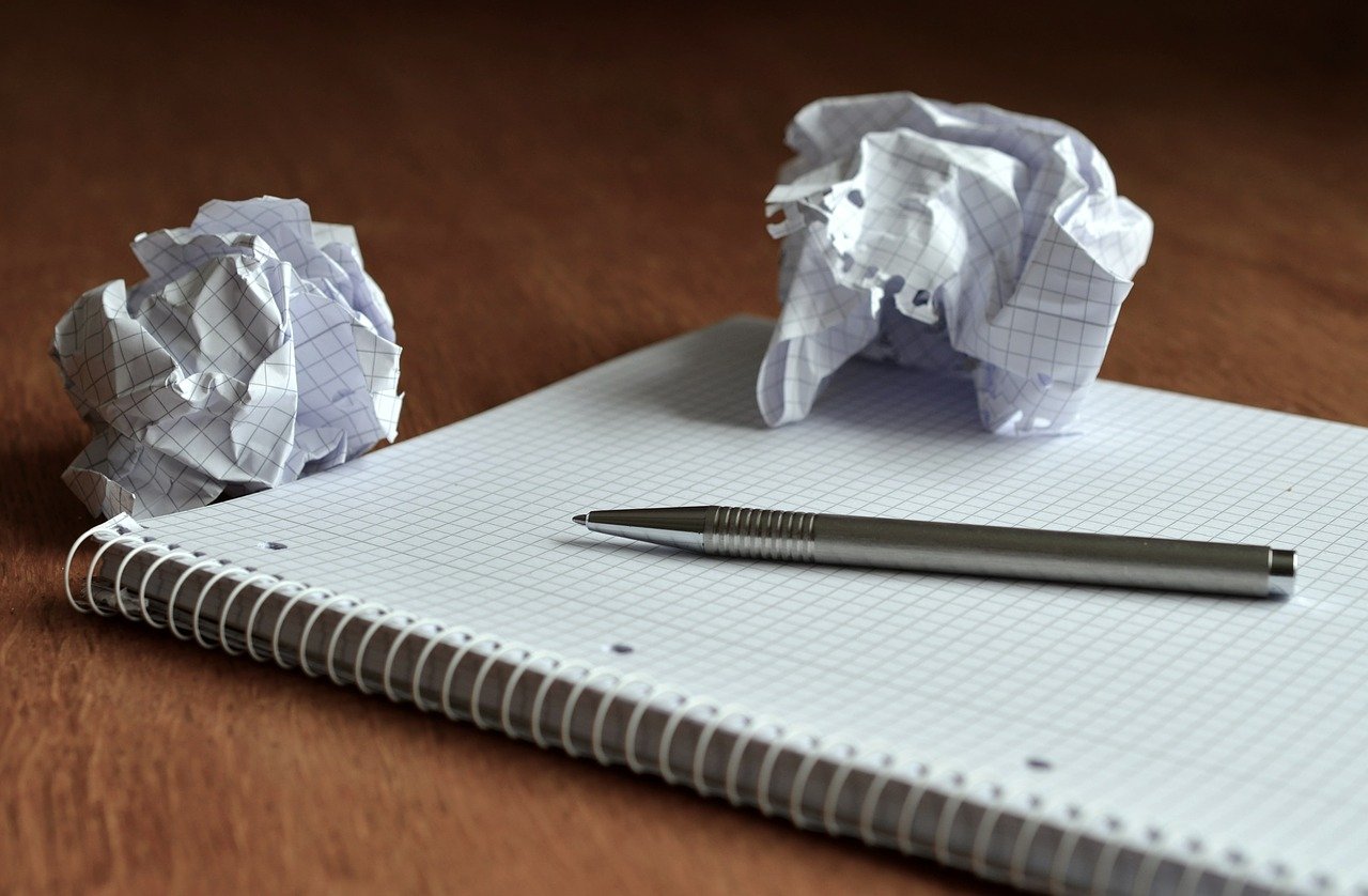 ノートとペン、くしゃくしゃに丸められた紙