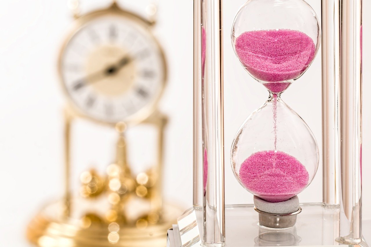 金の置き時計とピンクの砂時計