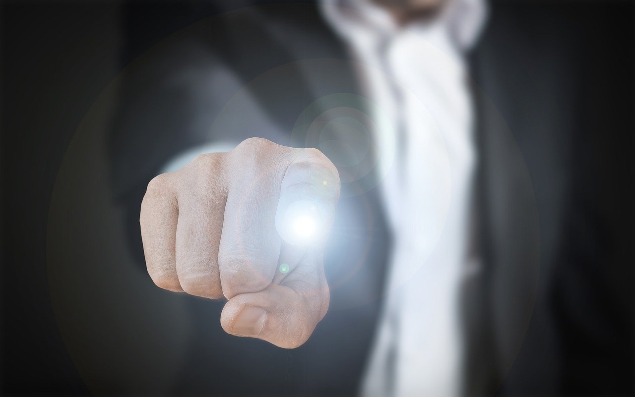 人差し指でボタンを押す仕草をするスーツの男性