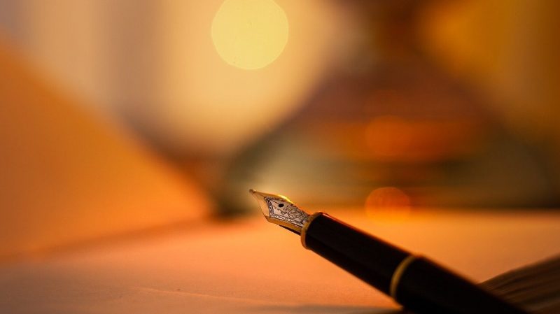 オレンジ色の光に照らされたノートと万年筆