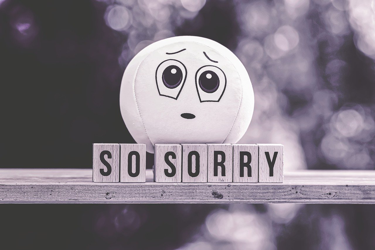 悲しそうな顔人形とSO SORRYの文字のモノクローム写真