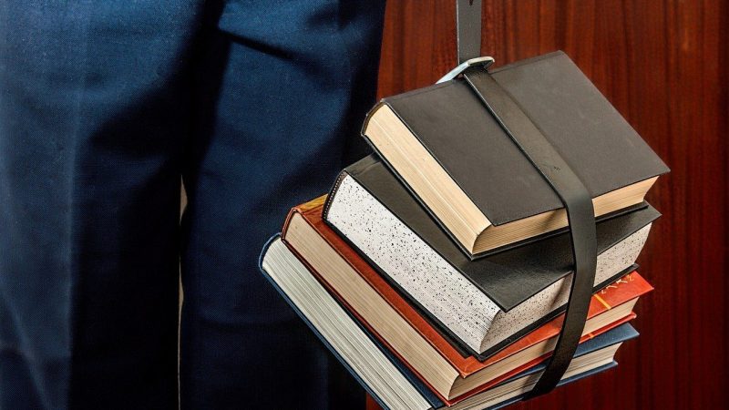 数冊の分厚い参考書を手に提げる男性