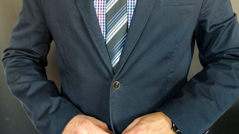 スーツの前のボタンをとめる男性
