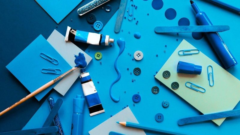 青い画用紙の上に散らばった青いクレヨン・鉛筆・絵具など