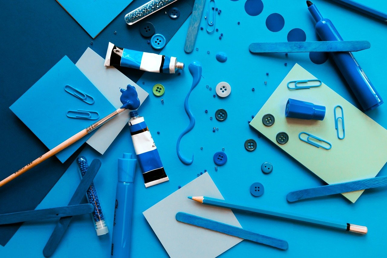 青い画用紙の上に散らばった青いクレヨン・鉛筆・絵具など