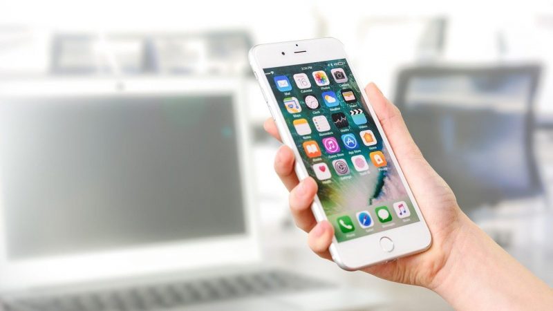 たくさんのアプリケーションのアイコンが表示されたスマホを持つ手